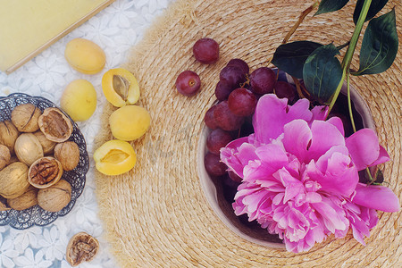 户外夏季野餐，法国风格，有新鲜的有机水果、牡丹花、白色亚麻布上的杏仁羊角、选择性焦点