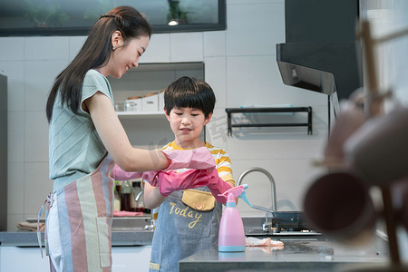 小学生打扫摄影照片_年轻妈妈指导儿子在厨房打扫卫生