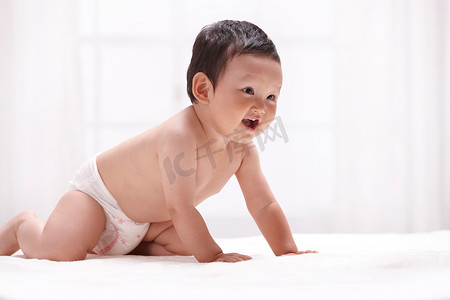 调皮图片摄影照片_一个婴儿趴在室内床上