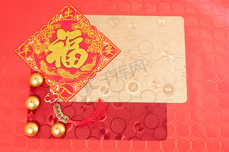 红色点缀装饰摄影照片_中国新年装饰用红色和金色饰品，红色桌上用红色和金色桌布点缀两支彩灯