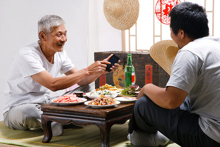 福字中摄影照片_农民父子坐在家中吃饭打电话