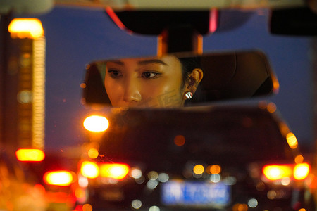车窗车灯摄影照片_堵车后视镜显示的青年女人