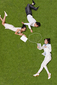 青年男女躺在草地上看电脑