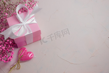 横屏周年庆海报摄影照片_礼物盒，顶部有鲜花和棒棒糖，粉红情人节背景。复制空间.