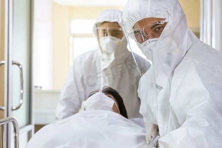 亚洲男性护士和医生，身穿ppe西服，头戴面罩，头戴担架床，头戴严重感染的考文鱼或眼镜蛇-19，向医院的隔离室进发.