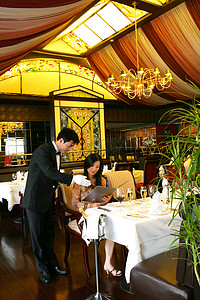 主题介绍摄影照片_酒店餐厅服务生向客人介绍菜单