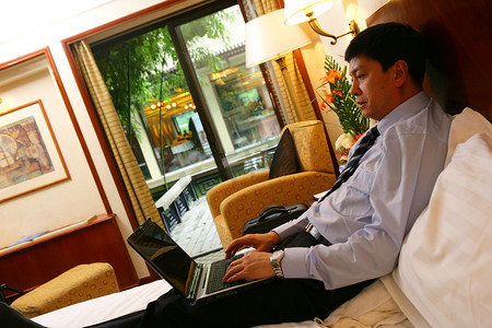 商务人士在酒店床上使用笔记本电脑