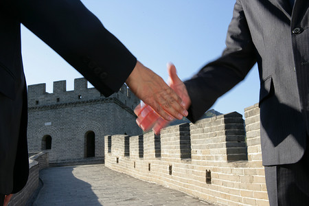 两位中外商务人士在长城上握手特写