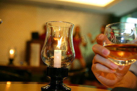 酒杯与蜡烛，以酒店酒吧表演者为背景