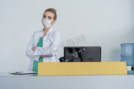 女接待员戴着医疗保护面罩在诊所服务台工作。流行病预防概念.