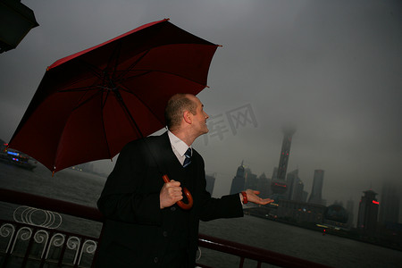 阴雨天外滩黄浦江边一位外国商务人士拿伞望天