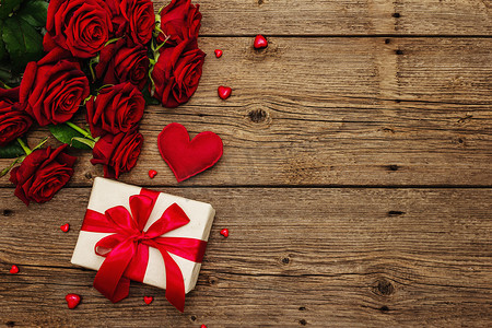 情人节玫瑰背景摄影照片_情人节贺卡背景与礼品盒，新鲜的勃艮第玫瑰和各种心脏。老式木桌。婚礼或生日的概念，文字的位置，平铺