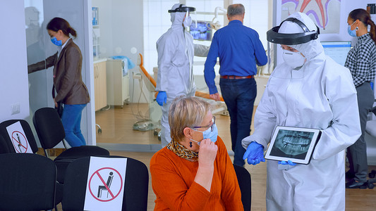 戴手套的护士摄影照片_头戴面罩的牙科医生在平板显示器上