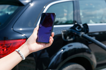 青年女人使用手机自助充电汽车