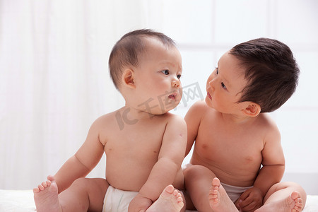人体白色摄影照片_两个婴儿坐在室内床上
