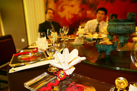 商务背景红色摄影照片_酒店餐具，以中外商务人士为背景