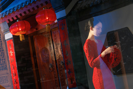 春节新年剪纸摄影照片_站在窗外拿剪纸的青年女人