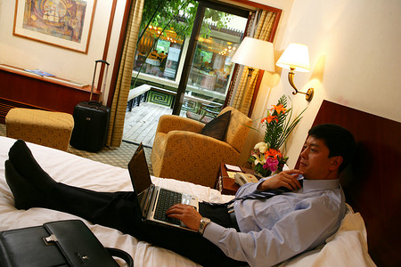 商务人士在酒店床上使用笔记本电脑