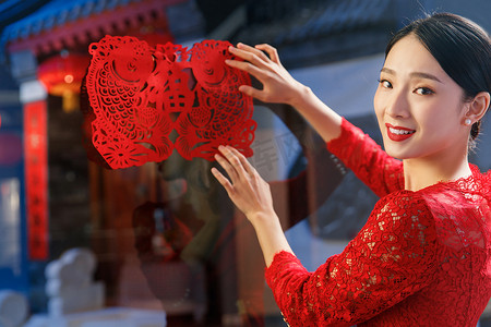 中式剪纸元素摄影照片_年轻女人过年贴窗花