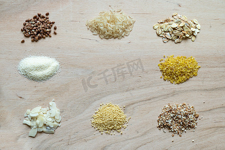 小麦麦片摄影照片_以木制背景为背景的谷类谷类谷物粥种子：荞麦、水稻、半甘蓝、小麦、粘性麦片、燕麦