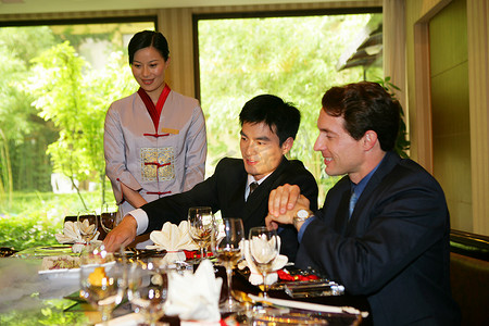 中外商务人士在酒店餐桌旁欣赏菜品