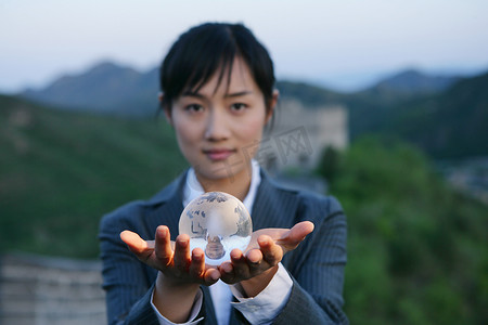 女商务人士在长城上手捧水晶地球