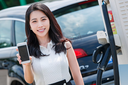 青年女人使用手机自助充电汽车