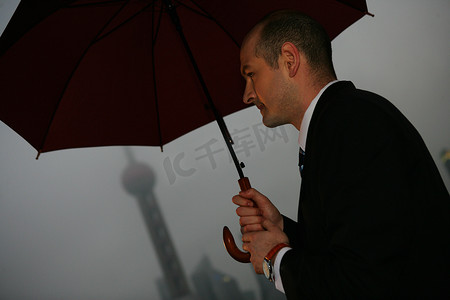 阴雨天外滩黄浦江边一位外国商务人士拿伞侧影