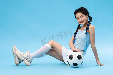蓝色背景简洁摄影照片_年轻女孩和足球