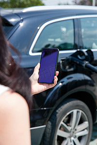 青年女人使用手机自助充电汽车