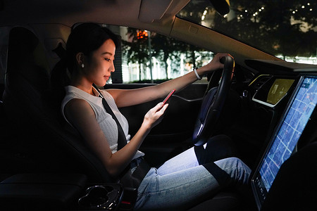 青年女人坐在汽车里使用手机