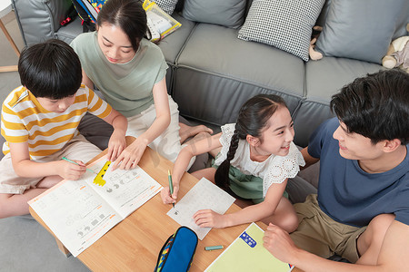 孩子背面俯视摄影照片_年轻父母辅导孩子做作业