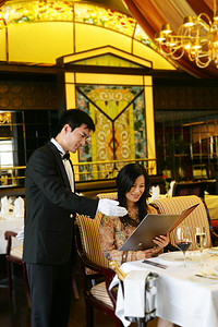 消费女性摄影照片_酒店餐厅服务生向客人介绍菜单