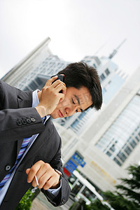 建筑手机摄影照片_上海浦东写字楼旁一位男商务人士打手机看手表