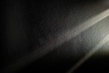 暗色的背景摄影照片_带有暗色纹理背景光束的光棱镜