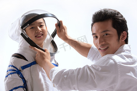 太空科技宇宙摄影照片_青年男人给小男孩穿宇航服