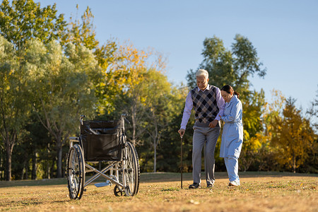 轮椅治疗摄影照片_护士搀扶老年人散步