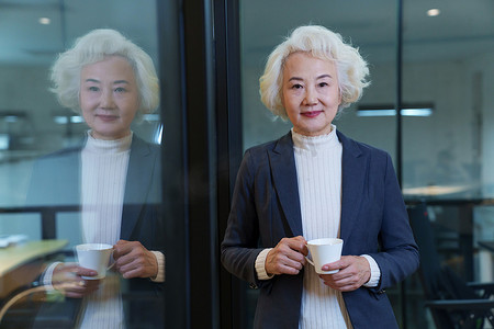 端咖啡的女人摄影照片_会议室内端着咖啡杯的商务老年女士