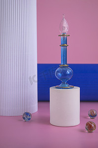 蓝色瓶子，白色的讲台上的香水粉红色的背景和柱子。化妆品展示。调味蓝色玻璃瓶，用香水或油作广告牌