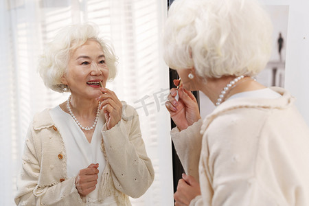 狭叶珍珠菜摄影照片_时尚的老年女人对着镜子化口红