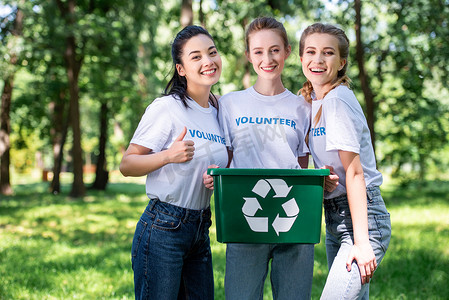年轻女性志愿者与回收盒显示拇指向上