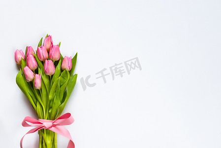 粉红色的郁金香花束的顶部视图, 用粉红色的丝带包裹在白色背景上。复制空间.
