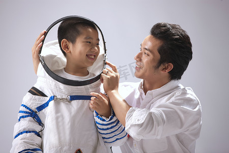 光荣的摄影照片_青年男人给小男孩穿宇航服