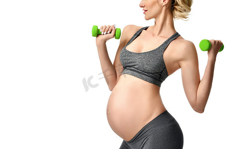 怀孕的妇女摄影照片_怀孕的妇女做运动伸展练习绿色的重量。孕产妇期望健康生活与体重控制概念