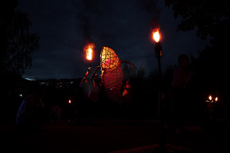 a dangerous and beautiful fireshow in the dark. artists in costumes of mythological creatures hold burning staffs and fans in their hands. juggling with fire