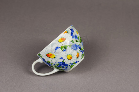带有灰色背景的陶瓷茶杯的简约构图。漂亮的杯子装饰着白色和黄色的雏菊.