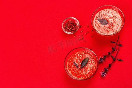 自制番茄汤。健康的素食，简约的概念。粉红色的胡椒玉米紫色的罗勒花明亮的红色衬垫背景，顶部视图