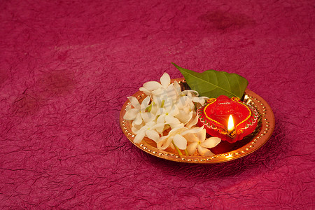 clay摄影照片_在Diwali庆典期间，Clay Diya灯被白花点亮。设计名为Diwali的印度印度教灯节贺卡.