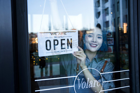 咖啡店标志摄影照片_咖啡店的女服务员挂营业标志