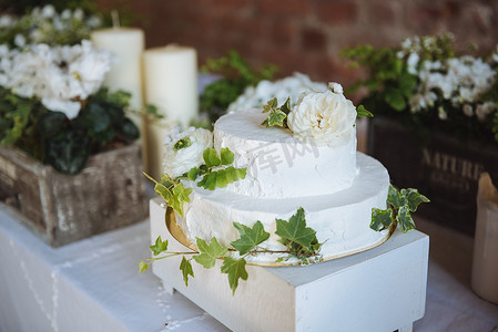 小花装饰摄影照片_婚礼蛋糕白色小花在绿叶上放在桌子上, candlesflowers 在盒子里结婚餐桌装饰